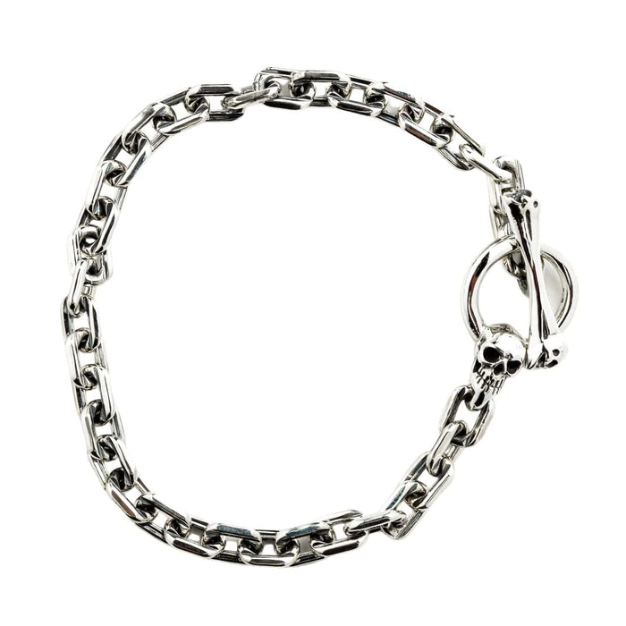 The polished sterling silver chain bracelet with skull T-bar clasp, laid in a curved shape.