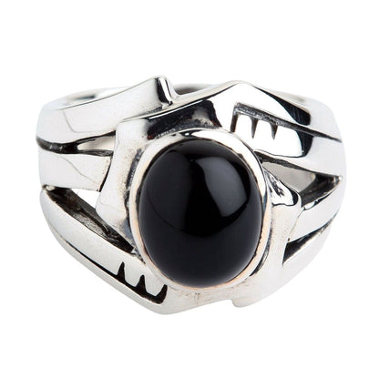 Close-up highlighting the flat black onyx stone centered within a wide sterling silver band featuring abstract cutouts.