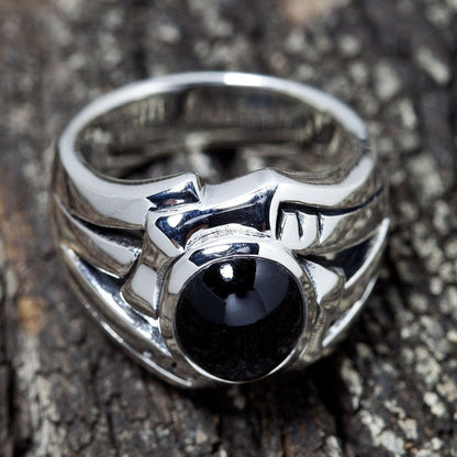 Resting on a textured wood surface, the heavy sterling silver frame surrounds a smooth, polished black onyx center stone.