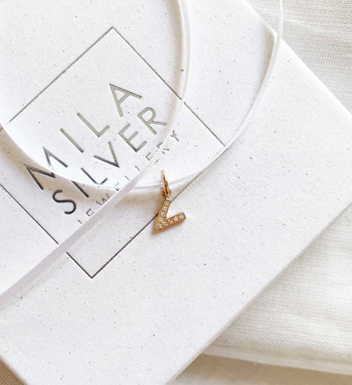 Diamantbokstav i guld placerad på en ask från Mila Silver.