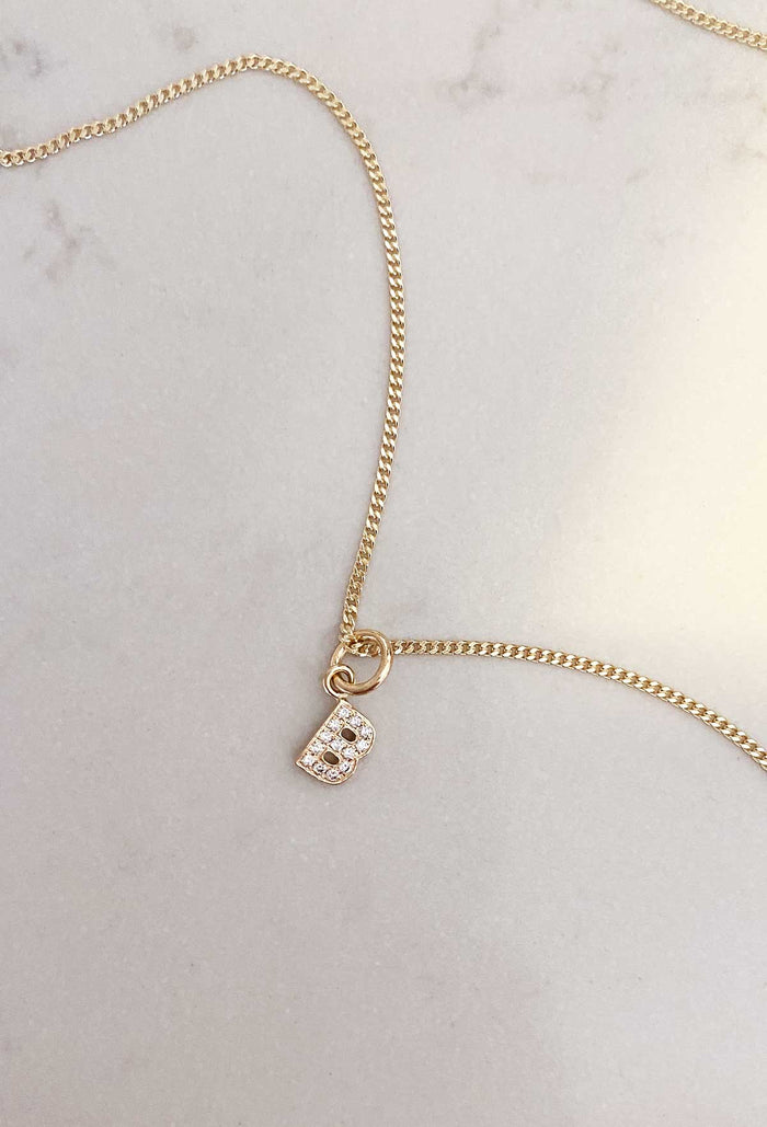 Utstansad BOKSTAVSBERLOCK i guld med diamanter i halskedja.