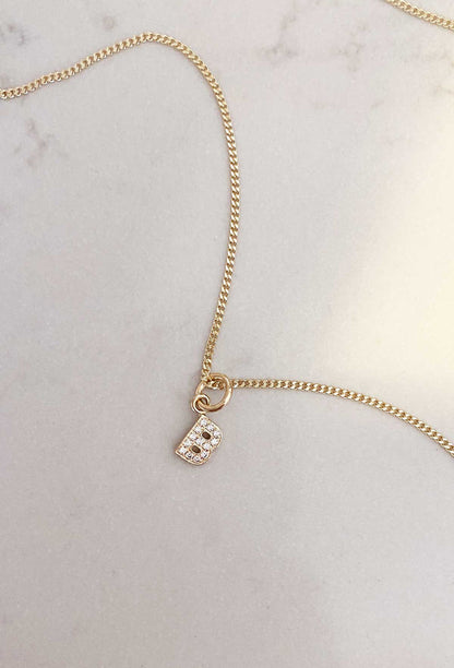 Utstansad BOKSTAVSBERLOCK i guld med diamanter i halskedja.