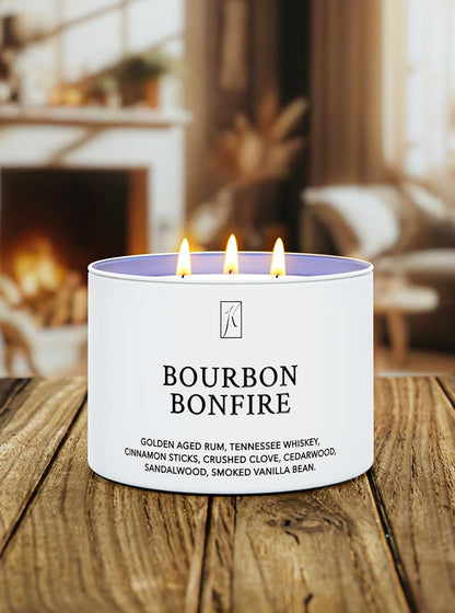 Candle labeled 'Bourbon Bonfire' on a wooden surface with a blurred background of a cozy room.