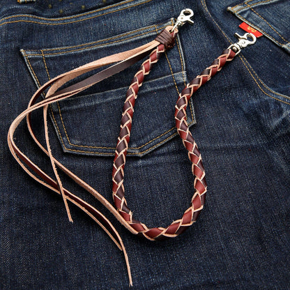 The braided leather wallet strap in a loop, showing the tribal zigzag braid pattern and lobster clasps on jeans.