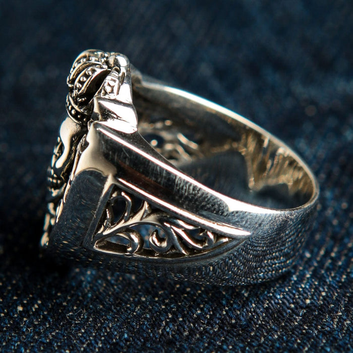 Profile view emphasizing the textured lower band and intricate side scrollwork of the solid .925 silver crowned skull ring.