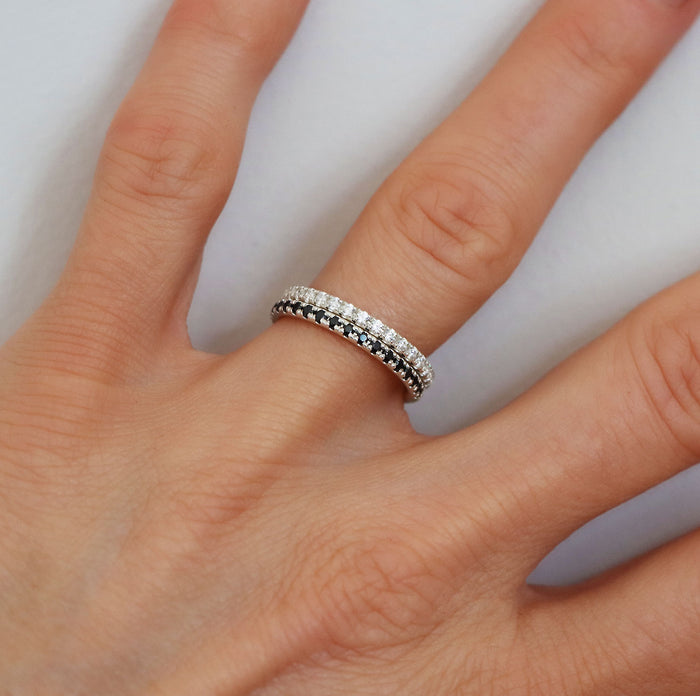 En ring med svarta diamanter och en ring med vita diamanter i  kombination på ett finger.
