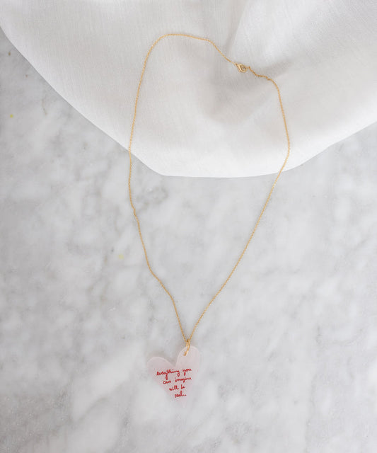 A "Everything You Can Imagine Will Be Real" necklace by WALD Berlin, with a pink heart on it.