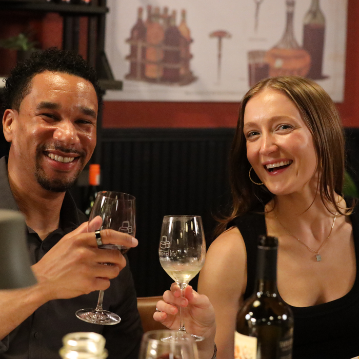 Two people enjoying wine in a cozy setting with a decorative wall in the background.