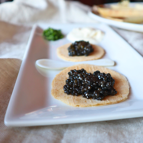 Caviar on crackers on a white plate with a blurred background