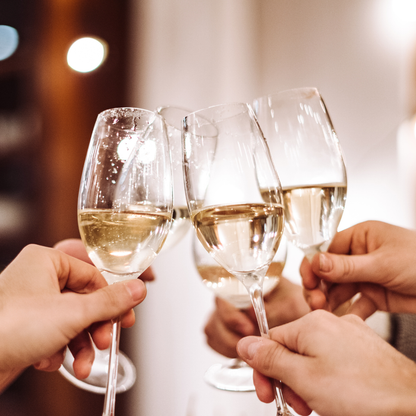 Four hands holding champagne glasses with a blurred background
