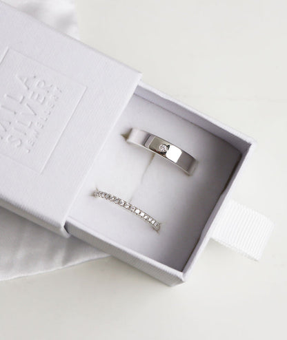Ett set med vigsel/förlovningsringar i silver med diamanter. Ringarna presenteras i en vit ringask.