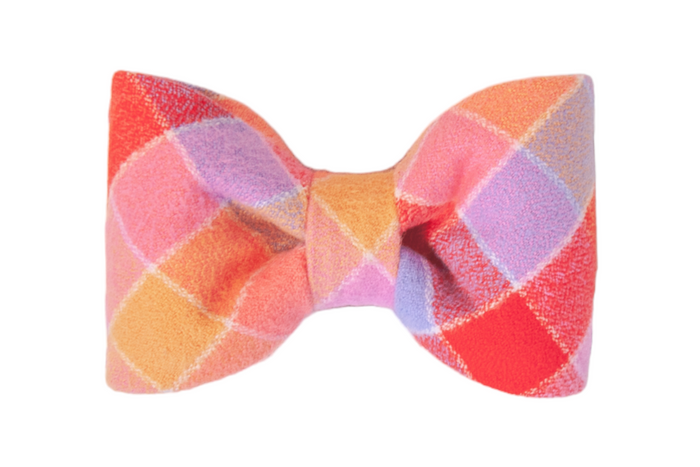 Soft flannel fabric dog bow tie with a classic silhouette, decorated in a pastel and jewel-tone plaid print. The symmetrical diamond pattern includes warm hues, creating a playful and eye-catching design.