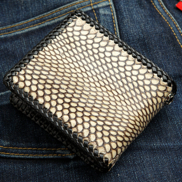 A handcrafted cobra skin wallet with detailed black leather lacing on the edges.