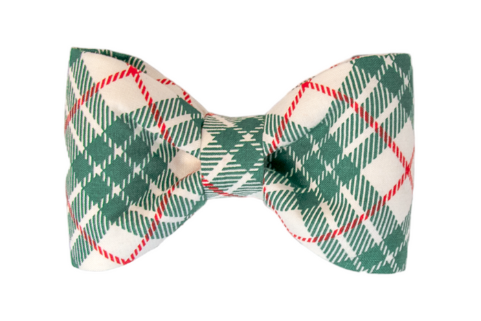 Close-up of a Christmas-themed fabric bow tie with a green plaid on light fabric. The bow tie is evenly shaped with crisp folds and a centered knot, creating a cheerful, seasonal accessory.