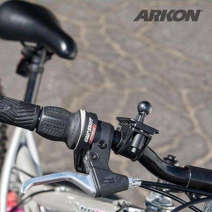 Close-up of a bicycle handlebar with black rubber grip, gear shifter, brake lever, and a Bike or Motorcycle Handlebar Mount for Garmin nuvi 40, 50, 200, 2013, 24x5, 25x5 GPS. Paved surface in the background.