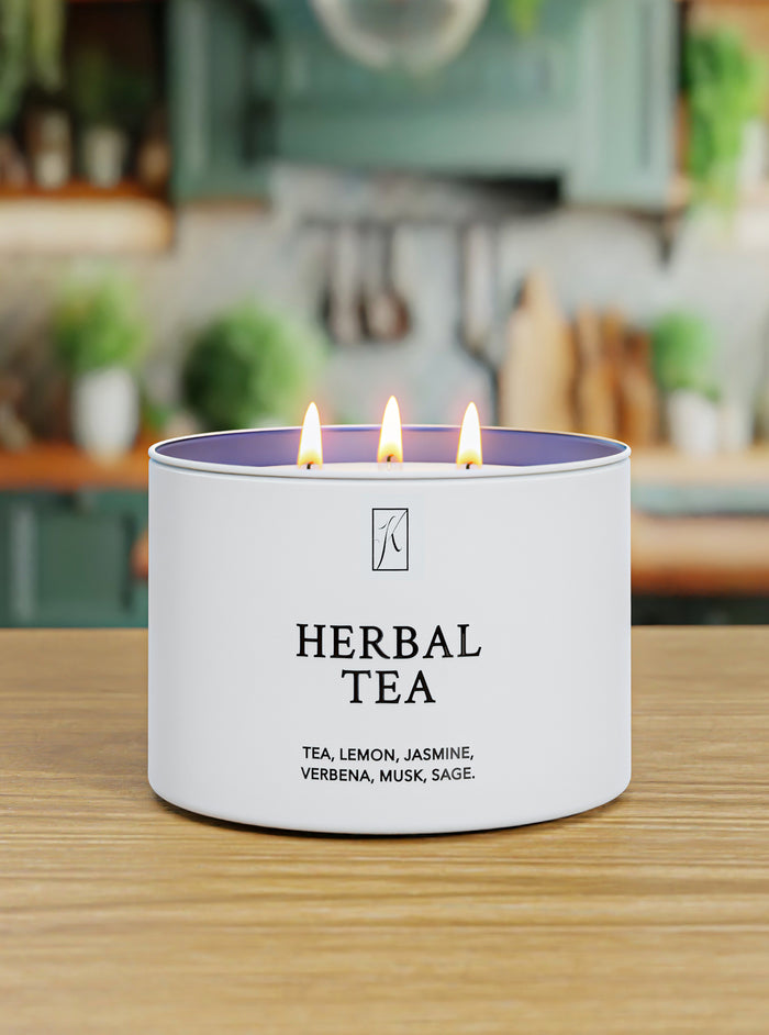 Candle labeled 'Herbal Tea' on a wooden surface with a blurred kitchen background