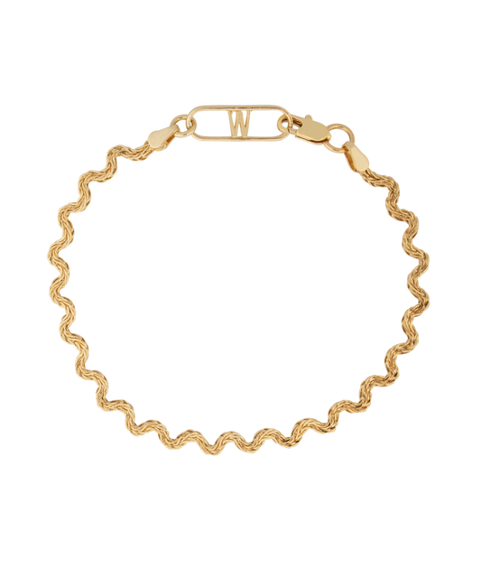 The Irina Gold Bracelet by WALD Berlin is an expertly crafted 18k gold bracelet featuring a wavy chain design and a rectangular clasp with the letter "W" on a black background, made in Germany.