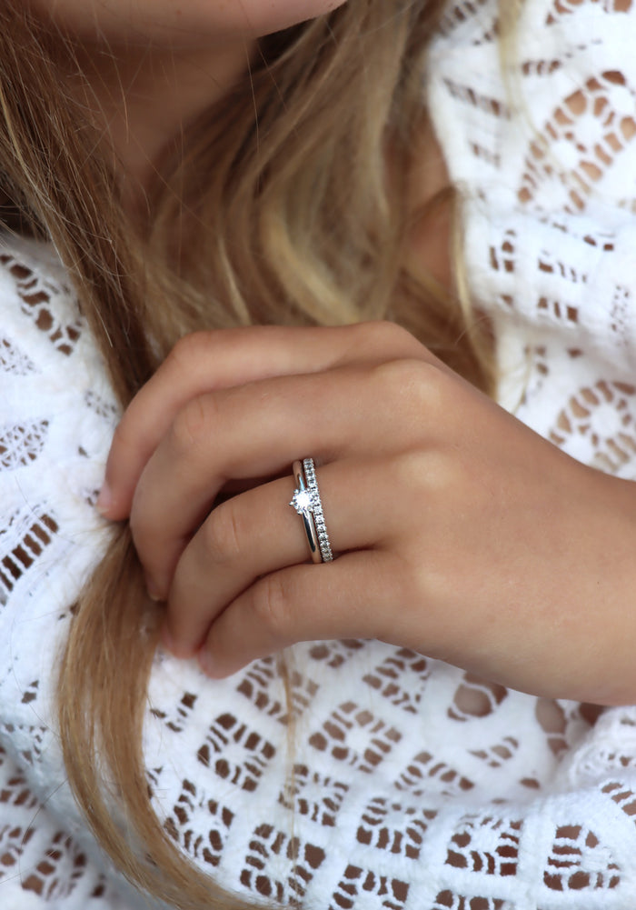 Tjej som bär två diamantringar som vigsel- och förlovningsring. Silverringar med diamanter. En alliansring med flera små diamanter och en ring med en diamant 0,25 ct.