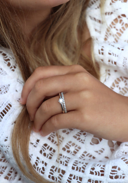Tjej som bär två diamantringar som vigsel- och förlovningsring. Silverringar med diamanter. En alliansring med flera små diamanter och en ring med en diamant 0,25 ct.