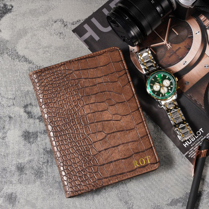 Brown crocodile-patterned wallet with a watch on a textured surface