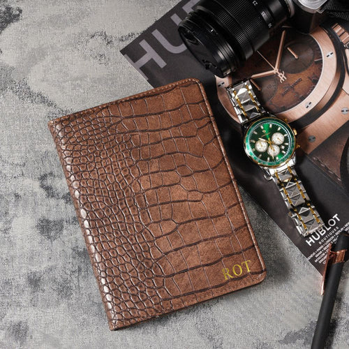 Brown crocodile-patterned wallet with a watch on a textured surface