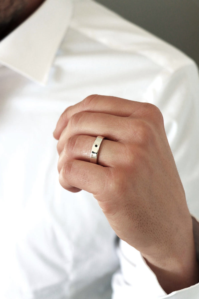 Man som bär silverring med svart diamant.
