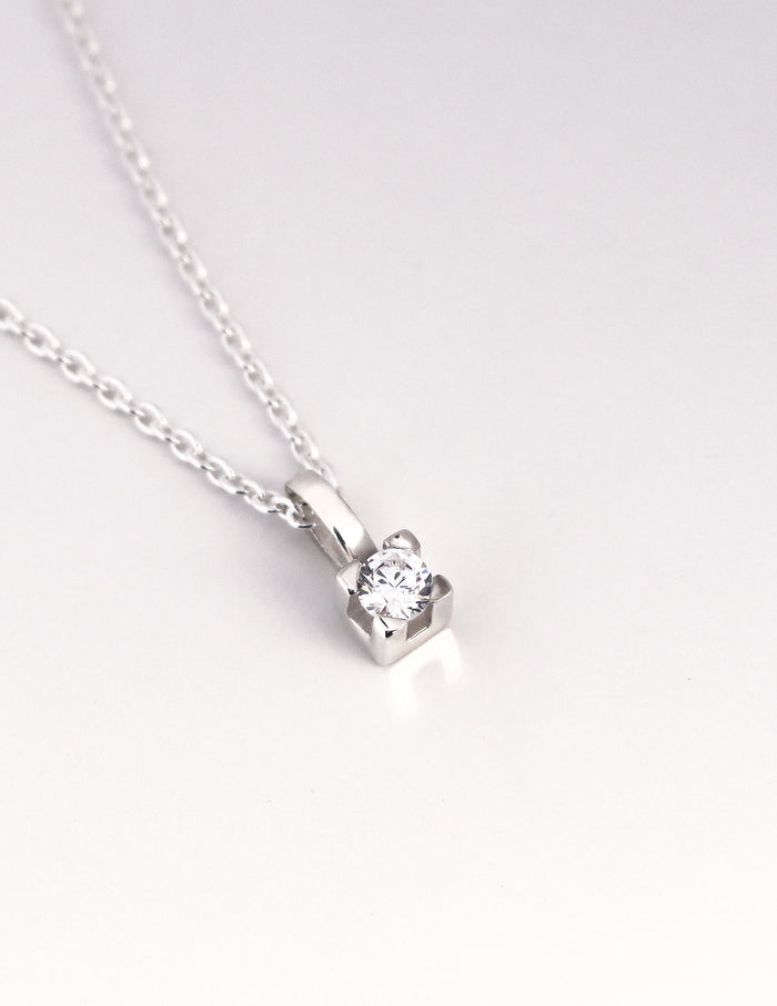 närbild på ett hängsmycke med gnistrande diamant i fyrkantig fattning.