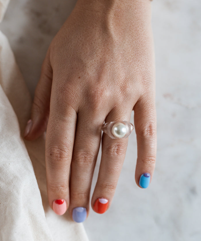 A woman's hand wearing a WALD Berlin Happy No No No Ring, showcasing the vibrant jewelry of Germany.