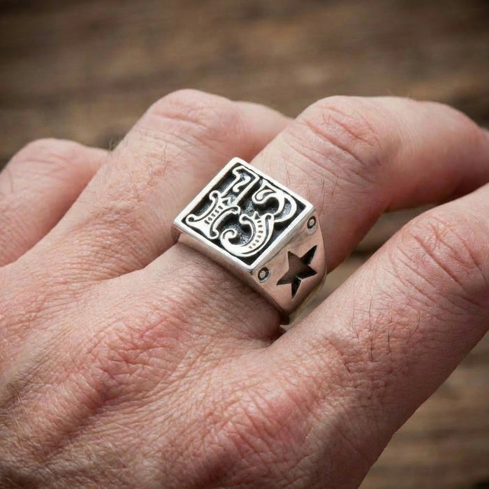 Gothic number 13 signet ring worn on a man's finger, showing the rectangular face and star cutout detail