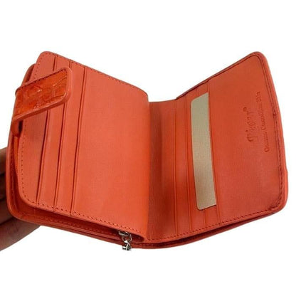 Hand holding open orange crocodile wallet revealing interior card slots, bill compartments, and River genuine crocodilian skin branding