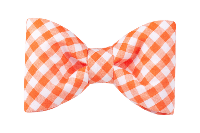 A bright orange and white gingham bow tie for dogs, with neatly curved edges and a gathered center. The soft cotton fabric adds comfort, while the cheerful plaid print brings playful charm to everyday outings.
