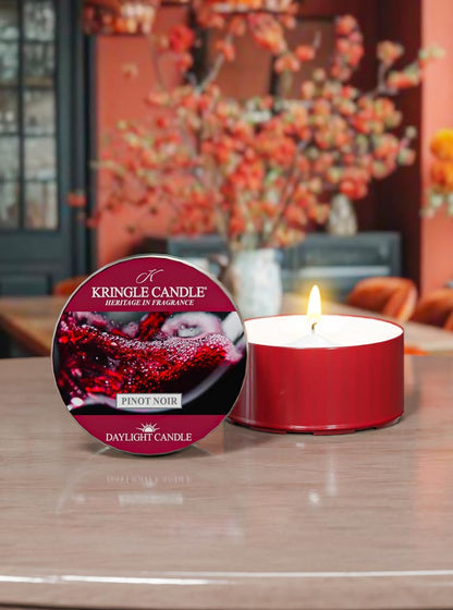 Red candle and its packaging on a table with a blurred decorative background