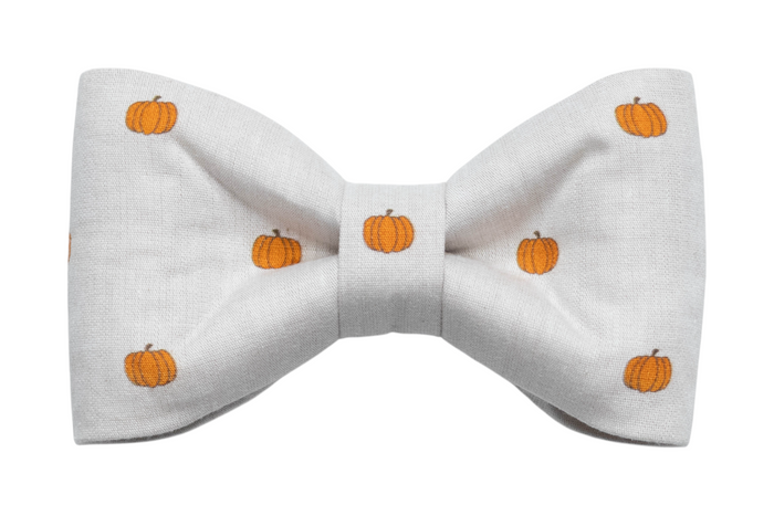 Soft beige dog bow tie with a clean, simple design featuring evenly spaced pumpkins. Its structured, classic shape makes it an ideal choice for dogs needing a touch of seasonal flair without loud colors—great for Halloween or cozy autumn outings
