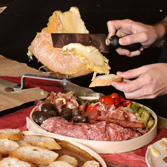Image of someone scraping raclette onto a piece of bread