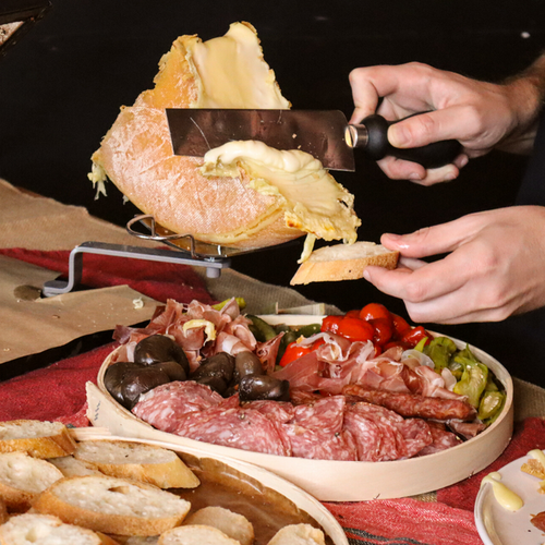 Image of someone scraping raclette onto a piece of bread