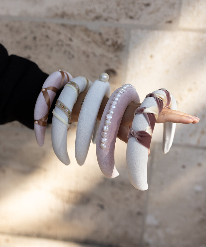 A woman is holding a pair of WALD Berlin Headband Swirl White bangles.