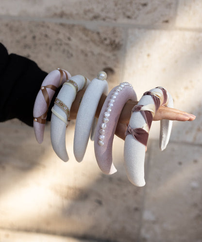 A woman is holding a pair of WALD Berlin Headband Swirl White bangles.
