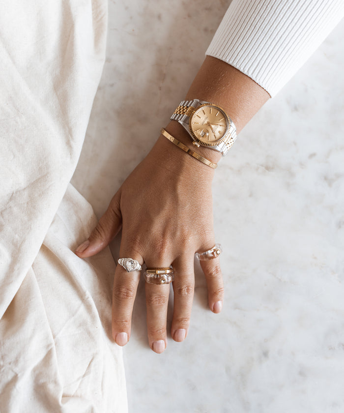 A woman's wrist adorned with a WALD Berlin jewelry, including a Shining Star Crystal Ring and watch.