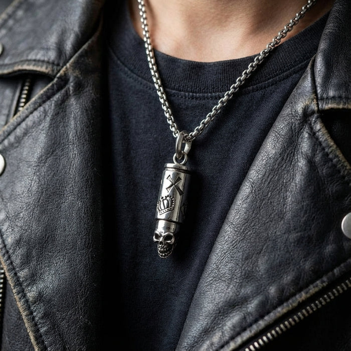 Silver skull bullet pendant necklace worn by man in black leather jacket and dark t-shirt, featuring engraved cylindrical design with skull detail on chain