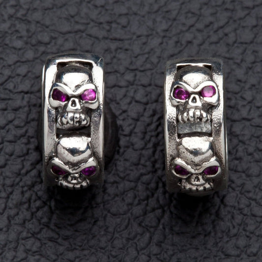 Pair of .925 sterling silver skull huggie hoop earrings, each 6mm band carved with a row of red-CZ-eyed skulls.