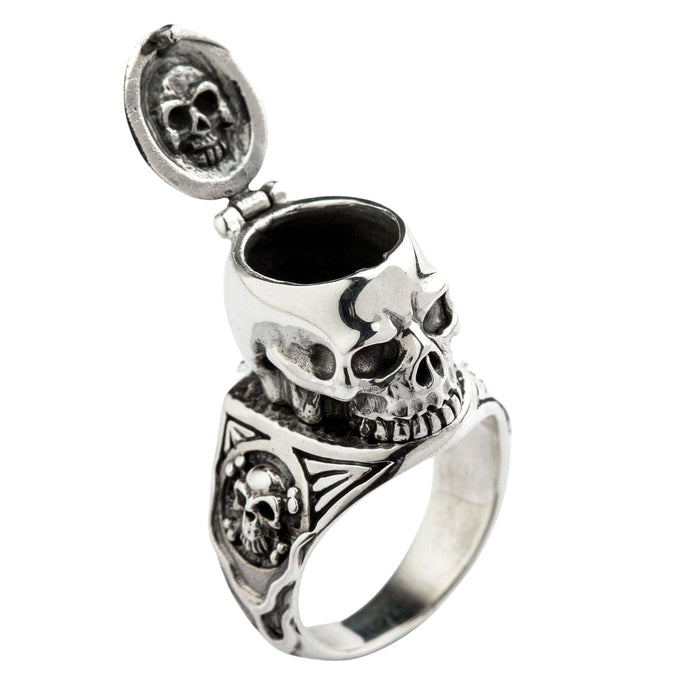 A solid sterling silver skull poison ring shown with its hinged top fully open, revealing the secret compartment inside.