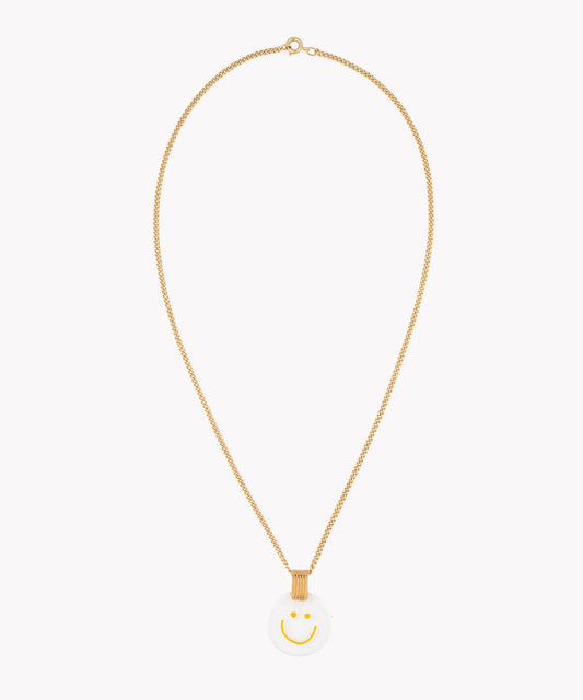 The Smilie Dude Medaillon Gold Necklace by WALD Berlin is an 18k gold-plated chain piece, showcasing a precisely crafted white circular medallion adorned with a yellow smiley face, made in Germany.