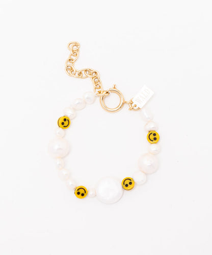 The WALD Berlin "Smilie Dude Pearl Bracelet with Extension" features yellow smiley face beads, sweetwater pearls, and a gold chain and clasp set against a pristine white background.