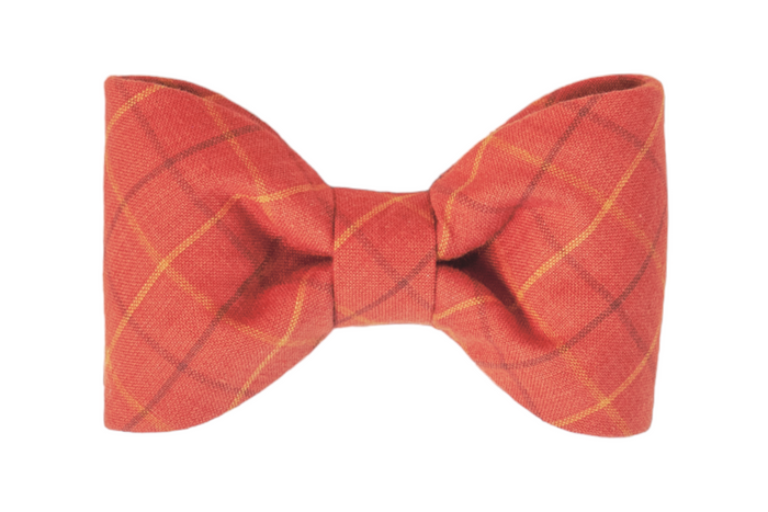 Soft-textured dog bow tie in earthy orange, featuring understated plaid lines in slightly contrasting shades for a refined, simple look.