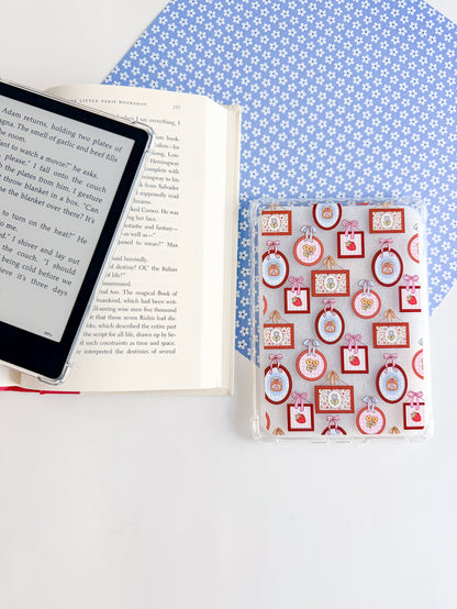 E-reader and book on a blue polka dot surface with a decorative box.