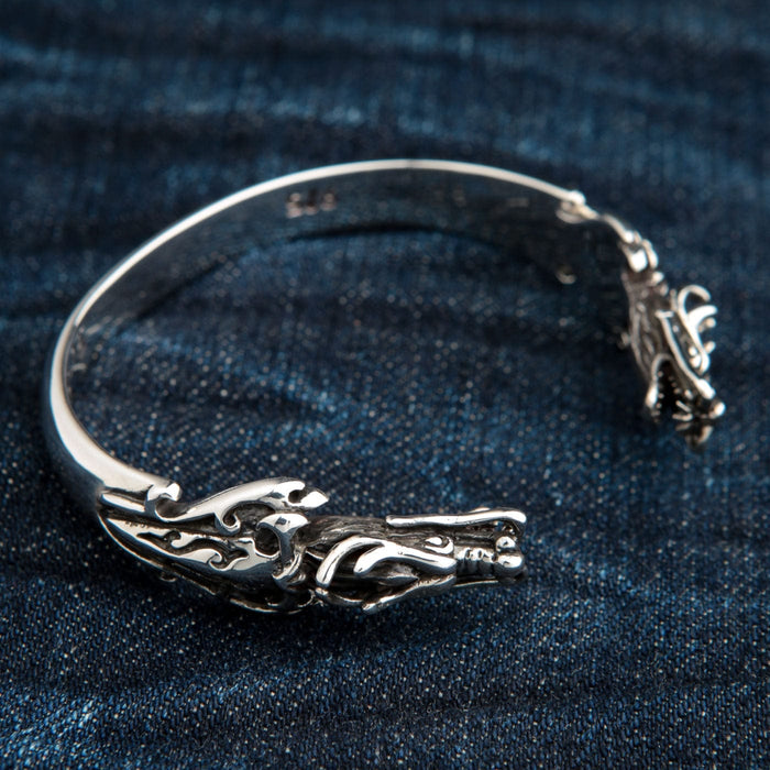 An angled view of the sterling silver dragon cuff, showing the detailed dragon head and polished band.