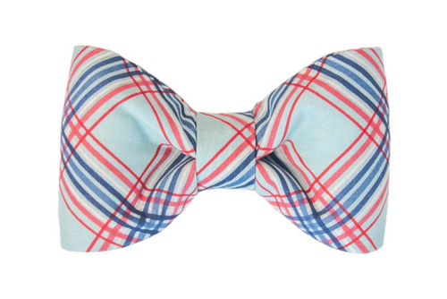 Close-up of a neatly tied plaid bow tie for your pup in light blue with intersecting red, white, and navy blue lines. The design has a crisp, preppy aesthetic.