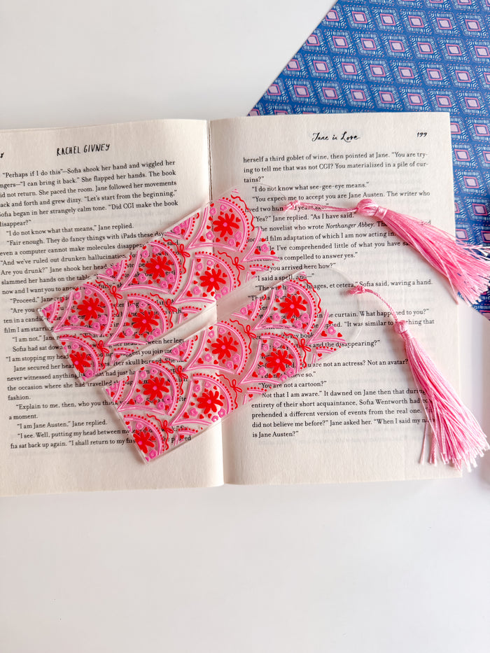Pink and red patterned bookmarks with tassels on an open book
