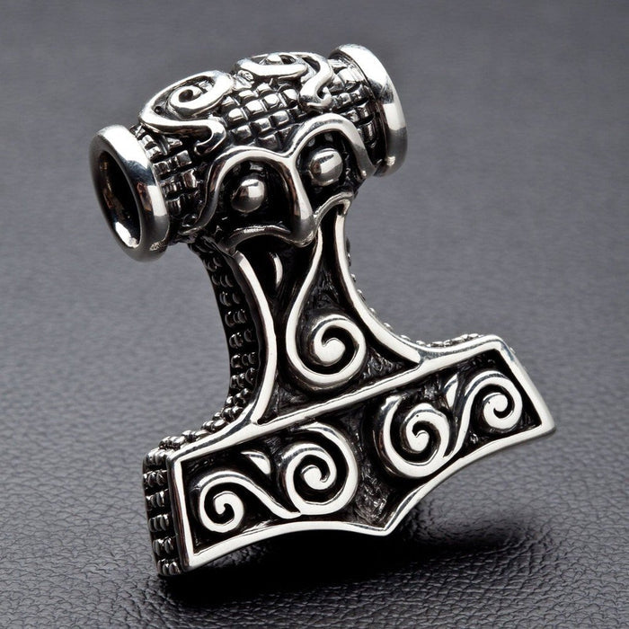 Detailed focus on the grid-textured top bail and face-like Norse carvings of the heavy .925 silver hammer pendant.