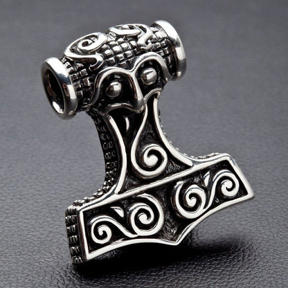Detailed focus on the grid-textured top bail and face-like Norse carvings of the heavy .925 silver hammer pendant.
